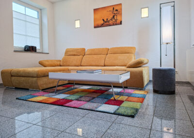Moderner Wohnbereich der Ferienwohnung Maison Marabu mit Sofa, Design-Sessel und farbigem Teppich im Ferienhaus Kamerun an der Elbe