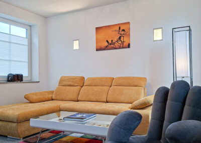 Gemütlicher Wohnbereich der Ferienwohnung Maison Marabu mit großem Sofa und Couchtisch in Damnatz nahe Elberadweg und Elbtalaue
